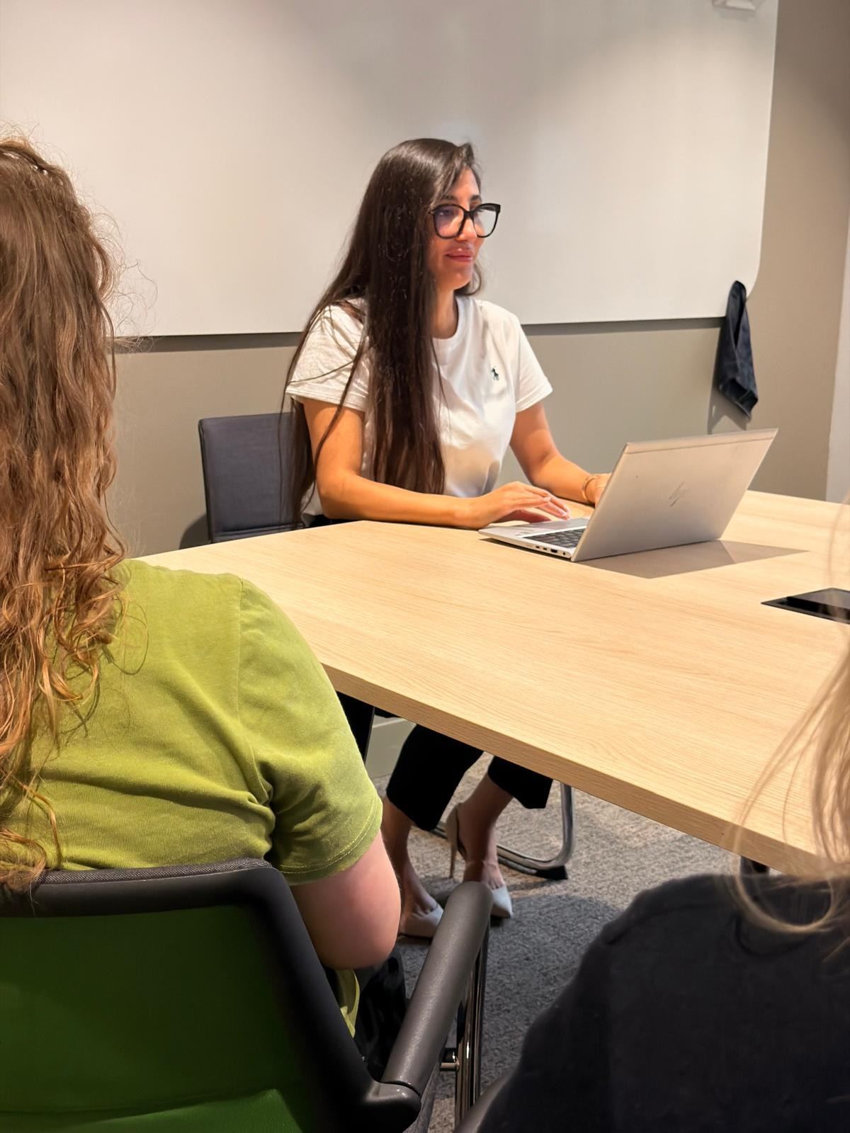 Rachida aan de vergadertafel met haar laptop, in overleg met collega’s